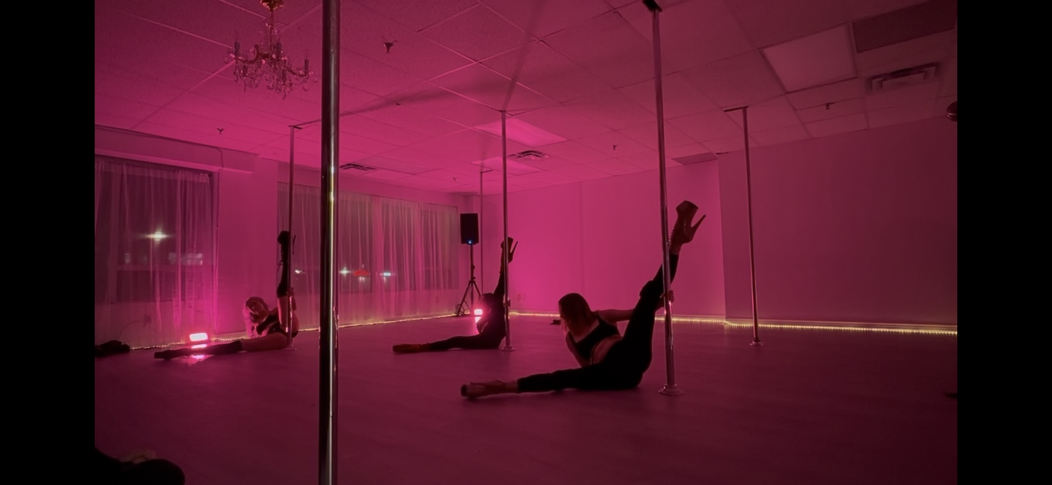 Body Evolution Studios performers in a synchronized pink-lit floorwork routine