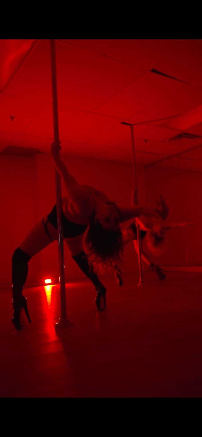 A performer creating a dramatic backbend shape beside a pole